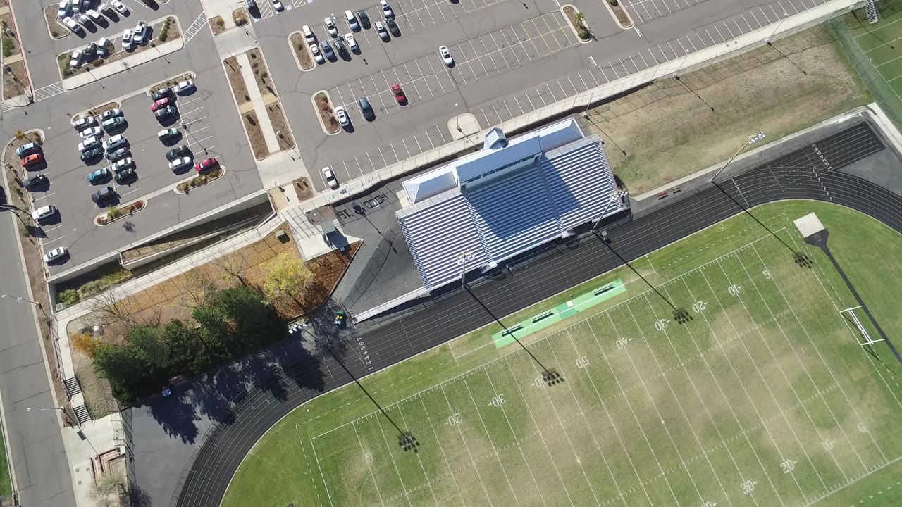 Overhead view of football field, running track, bleachers, and parking lots.