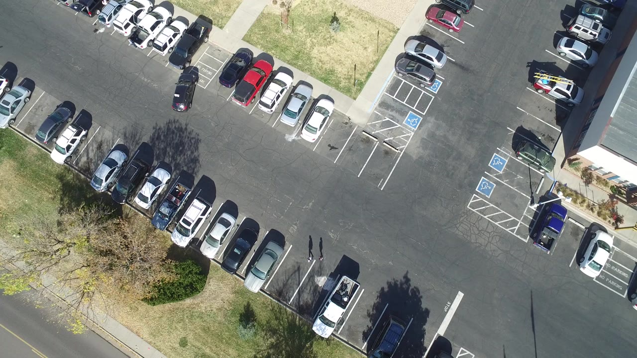 Top-down parking lot with parked cars, grass strips, and accessible spaces.