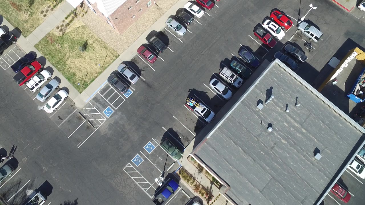 Top-down aerial view of a parking lot beside a flat-roofed building.