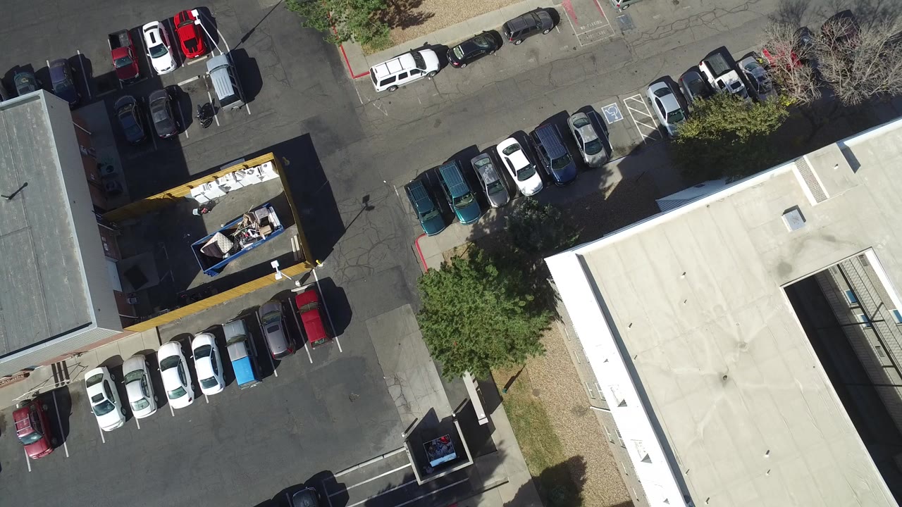 Top-down view of a parking lot beside a flat-roofed building.