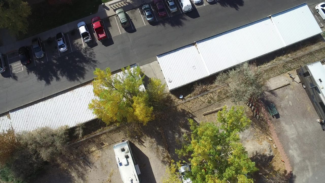 Hidden Lake, Colorado aerial frame with long white-roofed buildings, parked vehicles along the upper edge, autumn-colored trees, and no visible people.