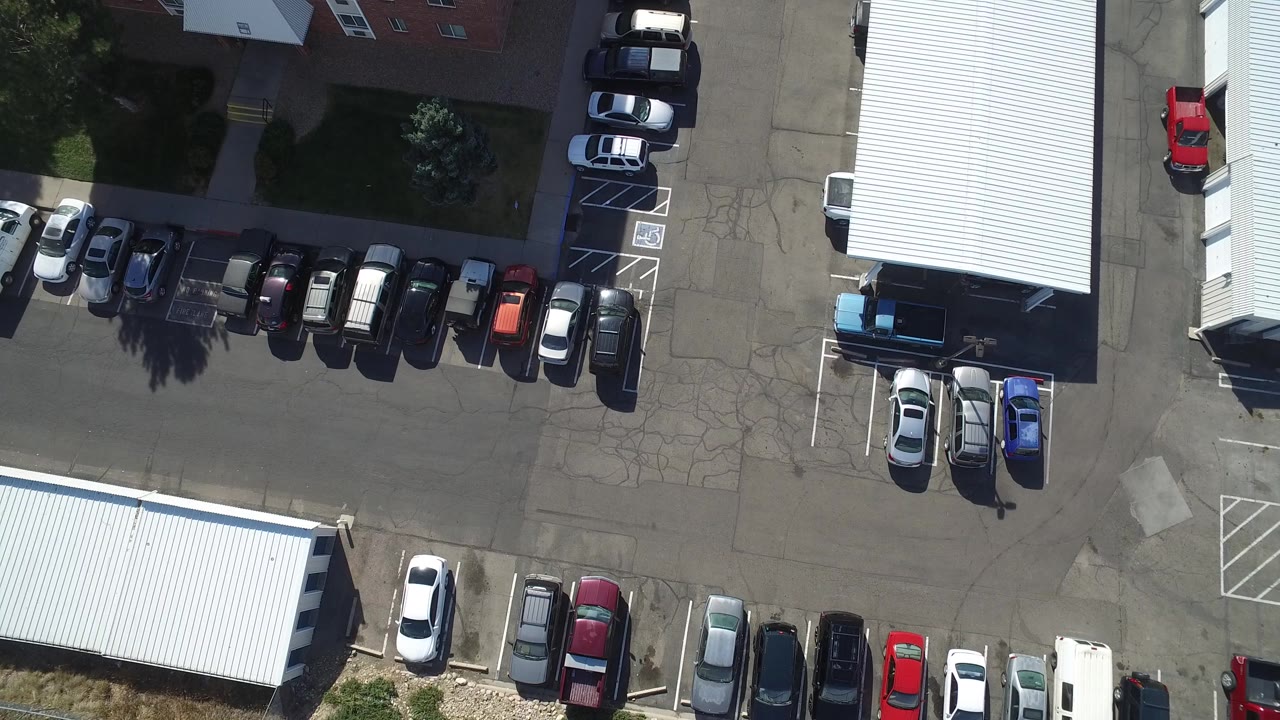 Top-down view of parking lots, white roofs, and parked cars.