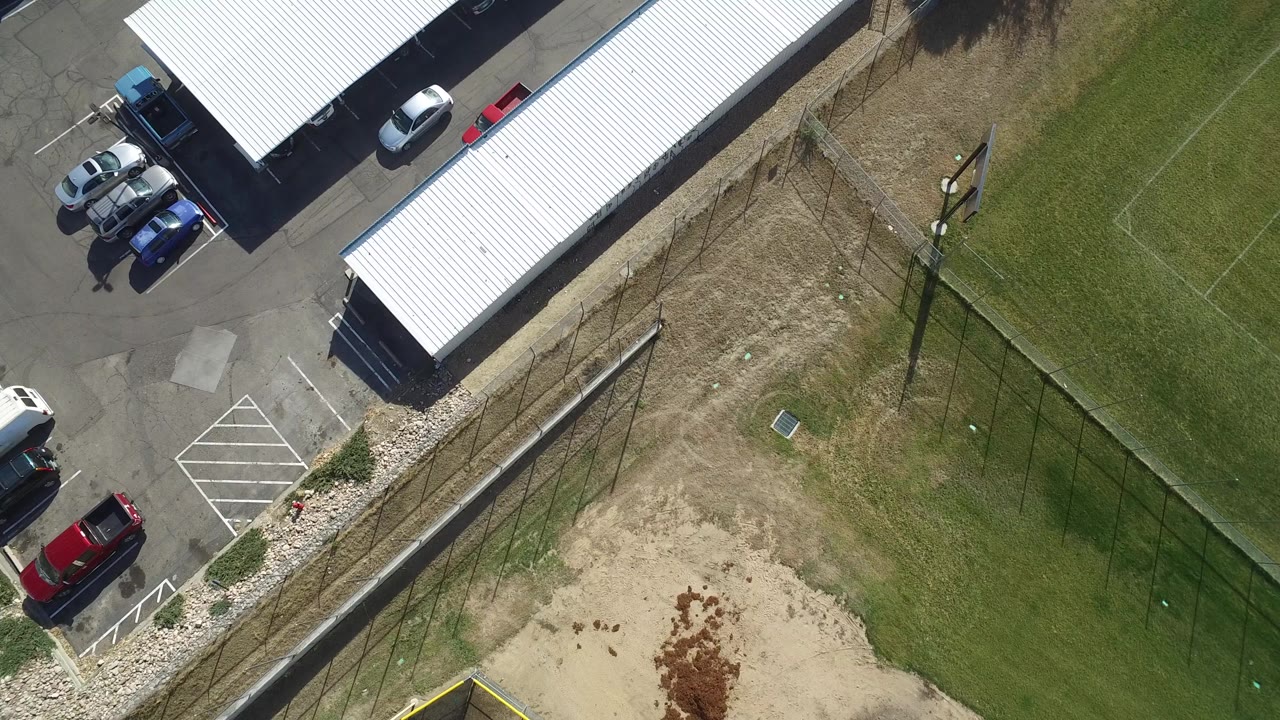 At 0:03, the Hidden Lake, Colorado overhead angle shows the white-roofed building along the left side of the frame, cars in the lot, a dirt clearing, grass, and no visible people.
