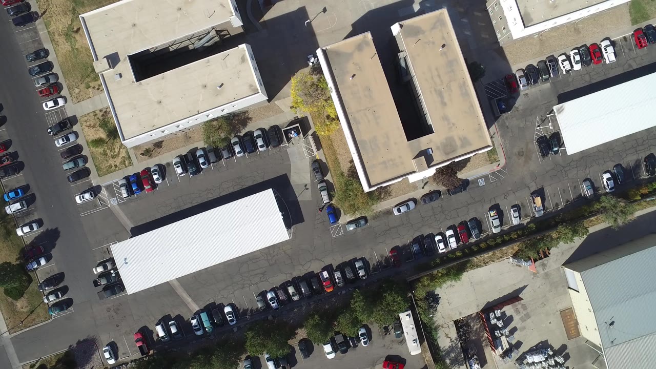 Top-down aerial view of low-rise buildings and parked cars.