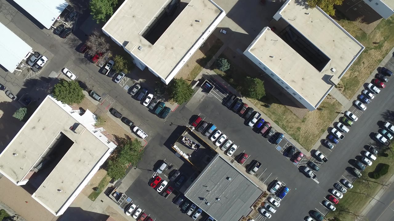 Top-down Hidden Lake, Colorado frame with two pale flat-roofed buildings, a darker roof structure, surrounding parked cars, access roads, and no visible people.