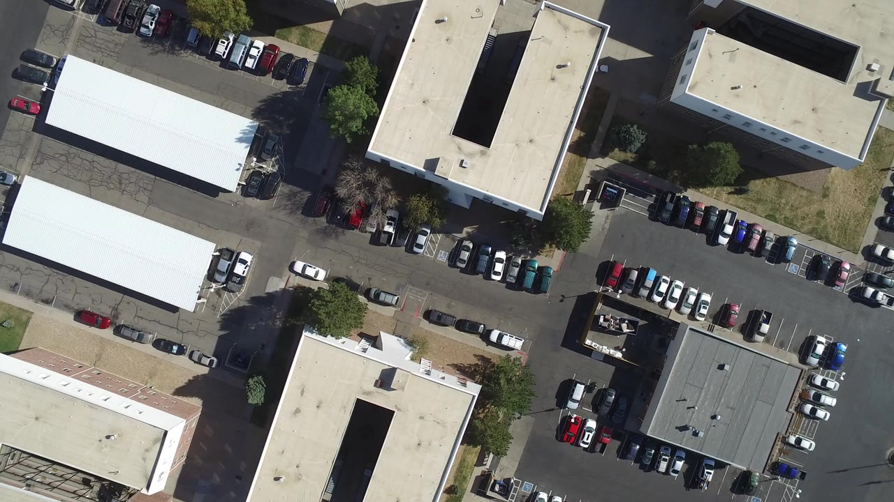 Overhead parking lot with white-roofed buildings and parked cars