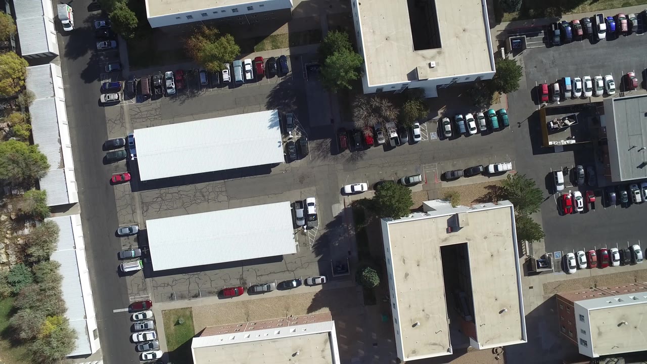 Overhead parking lots beside rectangular buildings and a narrow street.
