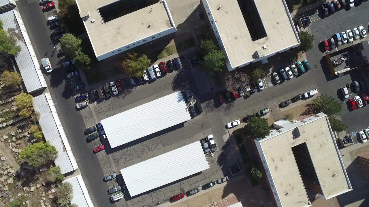 Top-down aerial frame over Hidden Lake, Colorado shows flat-roofed buildings, parking rows, trees, and a narrow street, with no visible people.
