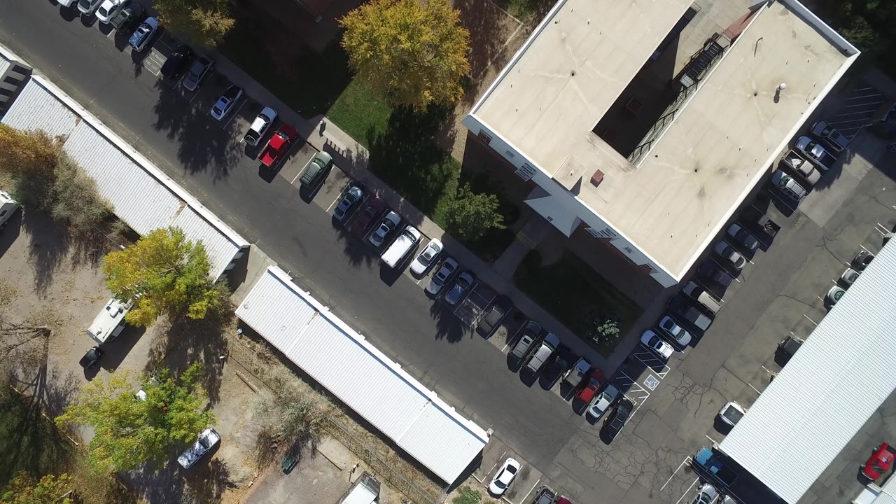 Top-down aerial view of a parking lot beside a flat-roofed building.