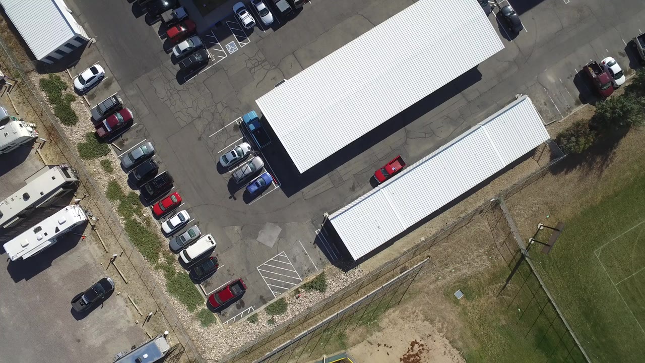 Overhead view of warehouses, parked cars, and a soccer field.