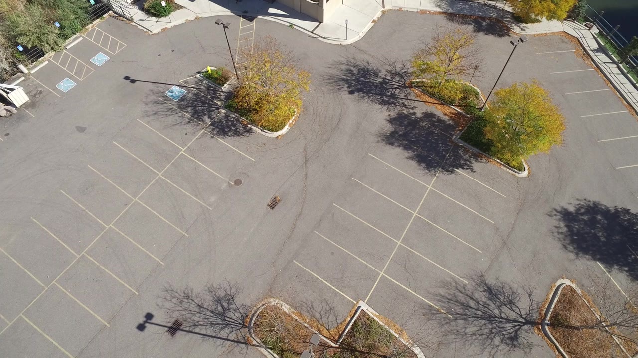 Top-down parking lot with landscaped islands and tree shadows.