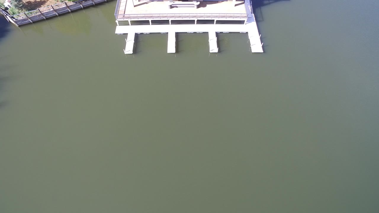 Overhead view at Hidden Lake, Colorado, with the upper edge of a white pier crossing into green water and no visible people.