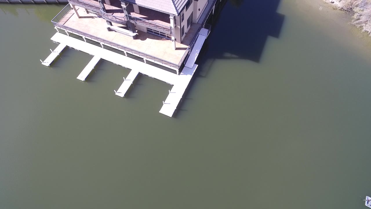 High view of a house dock and green lake water beside shoreline.