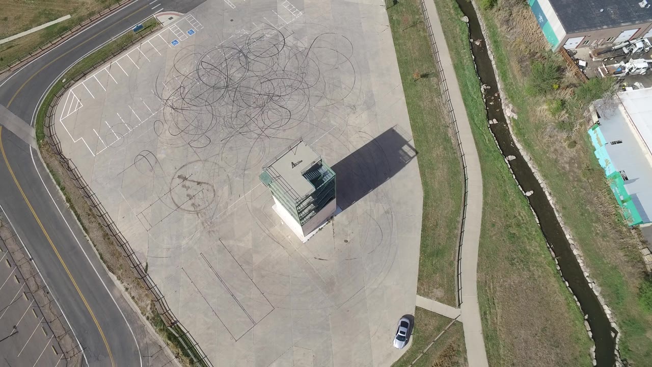 Drone view of empty parking pavement with one white car near the lower edge.