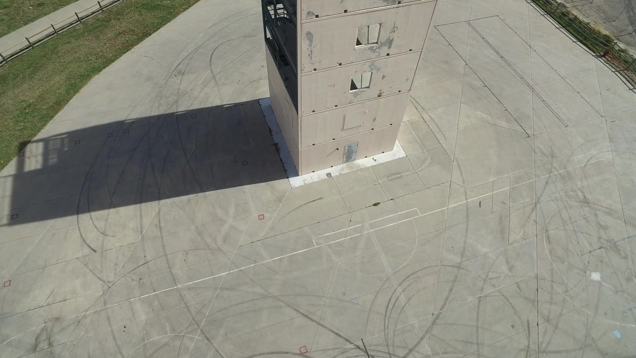 Aerial view of a tall pale structure casting a shadow across a concrete pad.