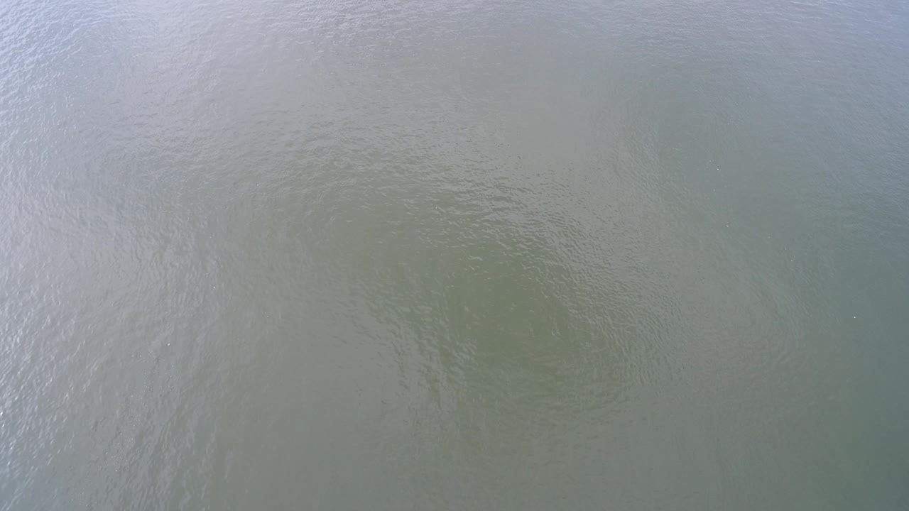 Muted green Hidden Lake water fills the frame with fine ripples and a cooler blue cast near the top edge, with no visible people.