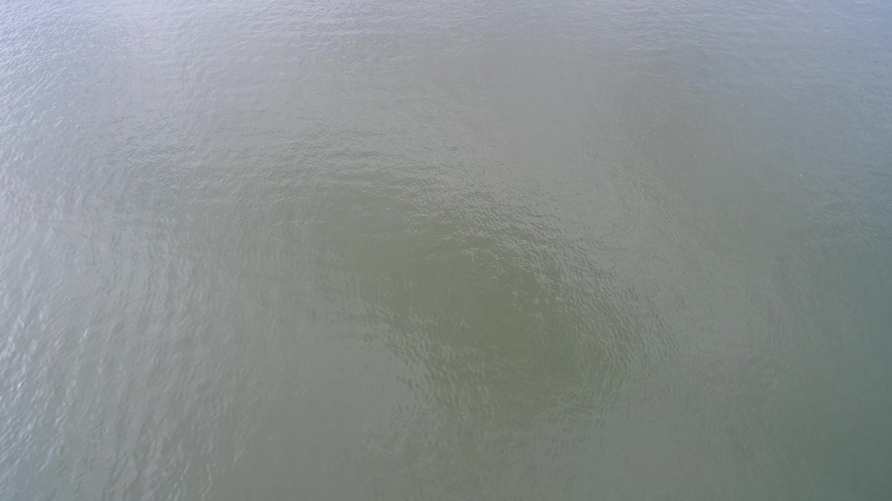 Hidden Lake water surface with pale reflective streaks crossing muted green-gray ripples, no visible people.