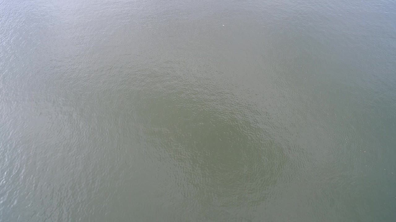 Overhead view of rippled green-gray water at Hidden Lake, Colorado, with pale reflected streaks near the upper left and no visible people.