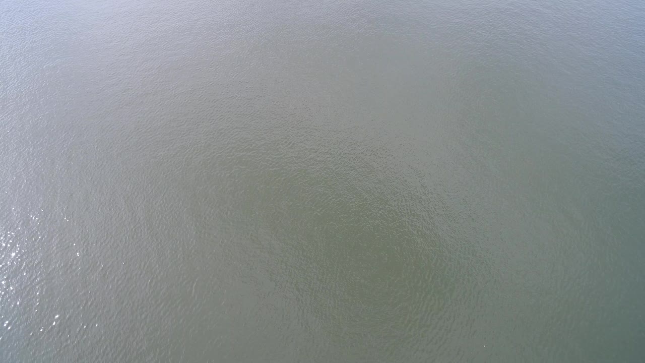 Overhead view of pale green and brown water at Hidden Lake, Colorado, with soft ripples and no visible people.