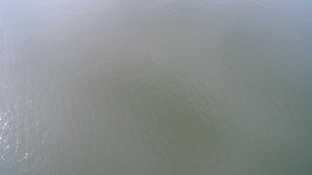 Murky Hidden Lake water seen from above, with a brighter vertical streak of reflected light and no visible people.