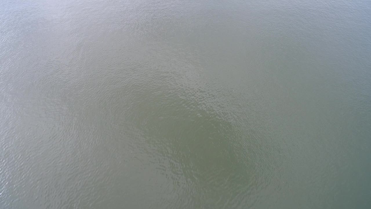 Muted Hidden Lake water fills the frame with soft ripple bands and a slightly darker green area near the lower center, no visible people.