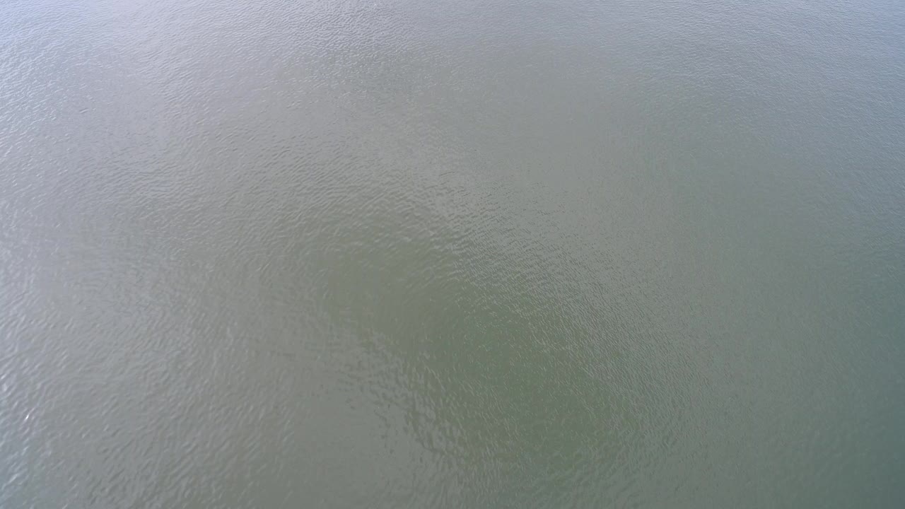 Opening frame of Hidden Lake, Colorado water seen as a green-gray surface with fine ripples, pale reflection, and no visible people.