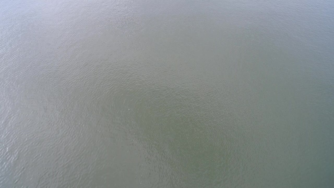 Overhead view of grey-green murky water at Hidden Lake, Colorado, with soft sunlight on the surface and no visible people.
