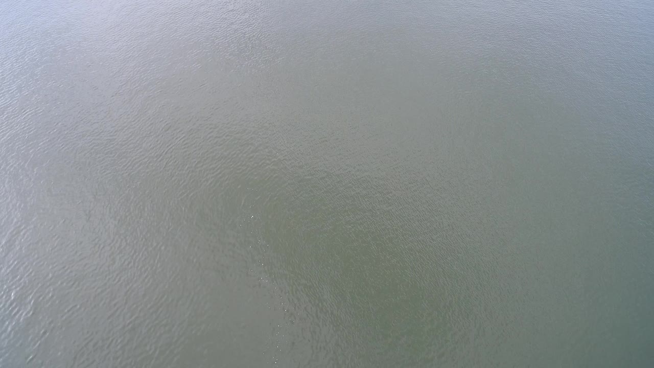A later overhead frame shows Hidden Lake water with a pale reflective band near the upper area and no visible shoreline or people.