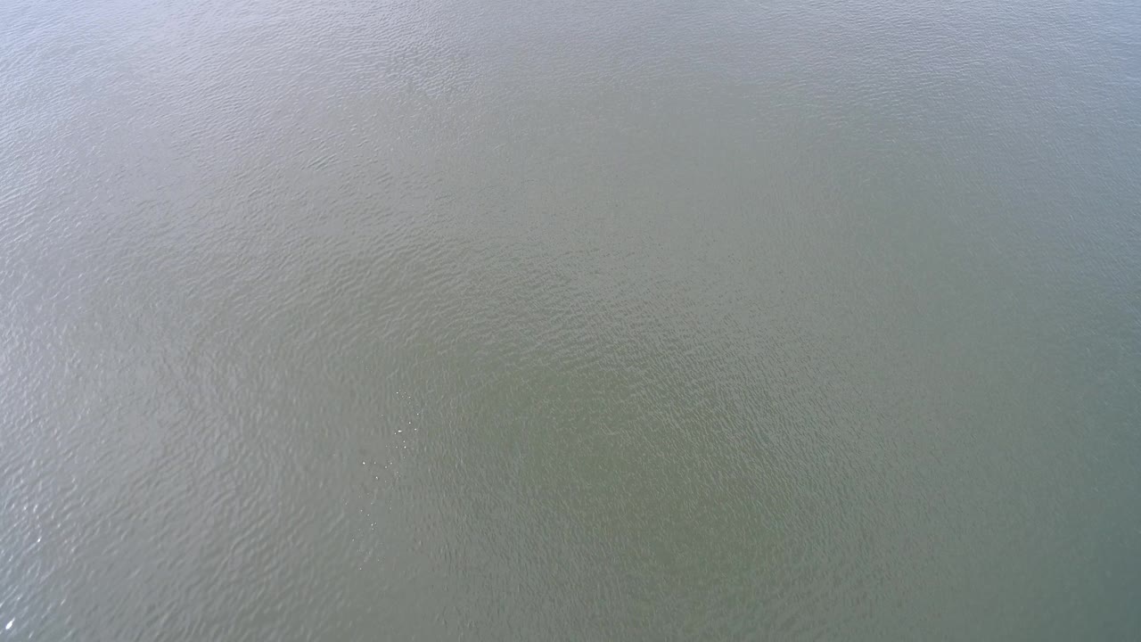 Aerial frame over Hidden Lake, Colorado, showing a muted water surface with faint diagonal ripple patterns and no visible people.