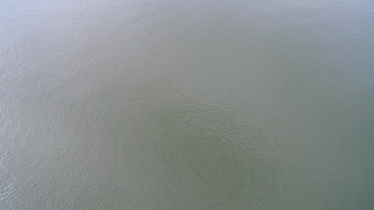 Overhead view of green-blue water at Hidden Lake, Colorado, with fine ripples and pale reflected light near the left side, no visible people.