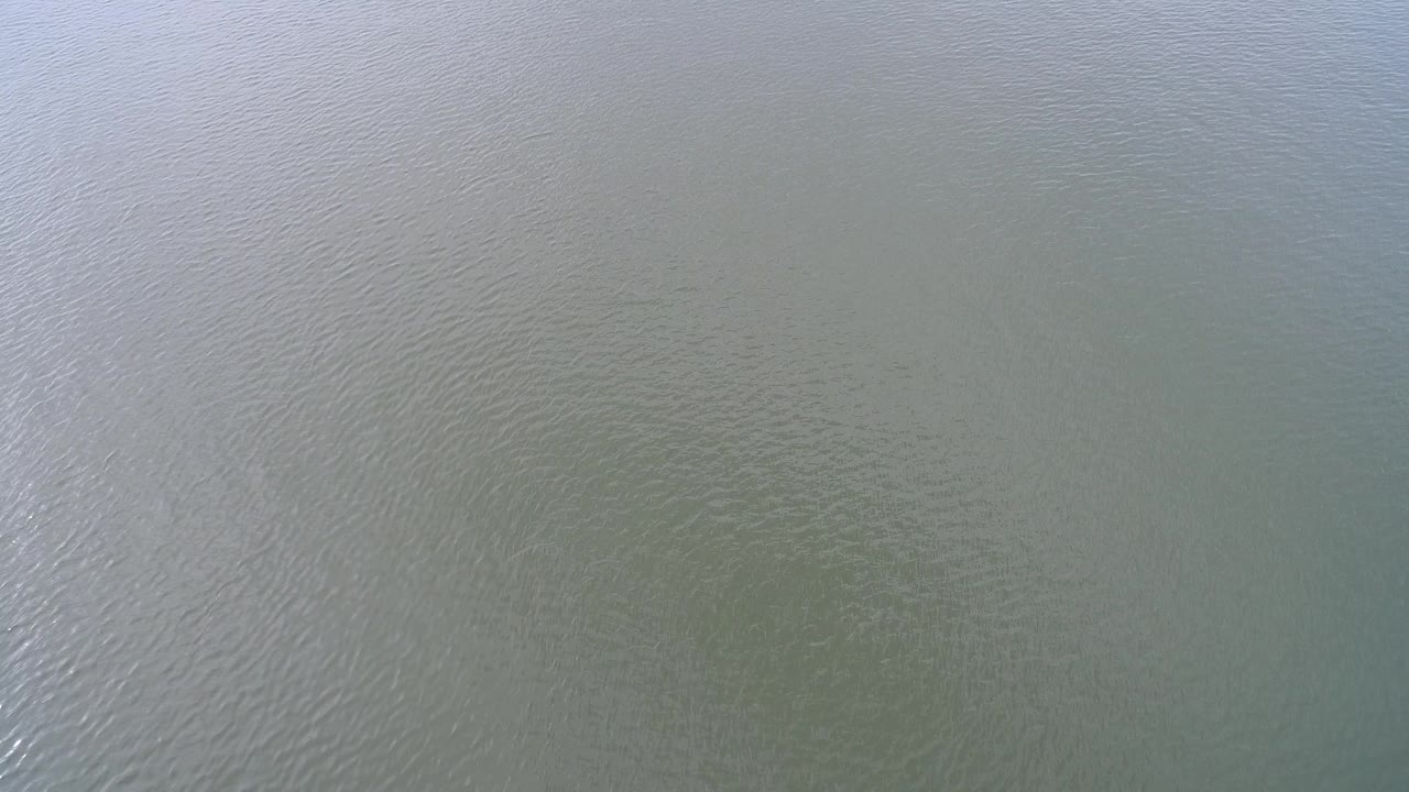 High view over Hidden Lake, Colorado showing a muted water surface with faint sun reflection and no visible people.