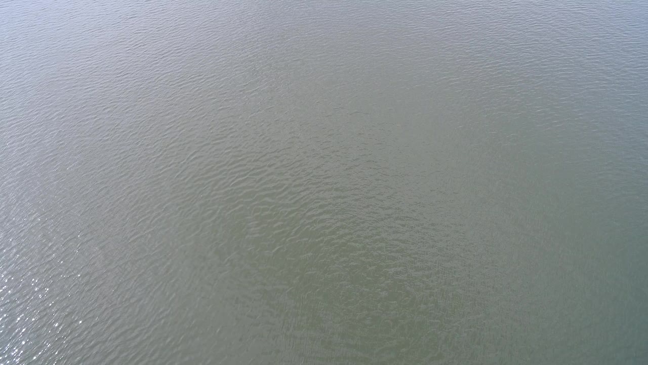 Pale blue-green rippled water with sun glint