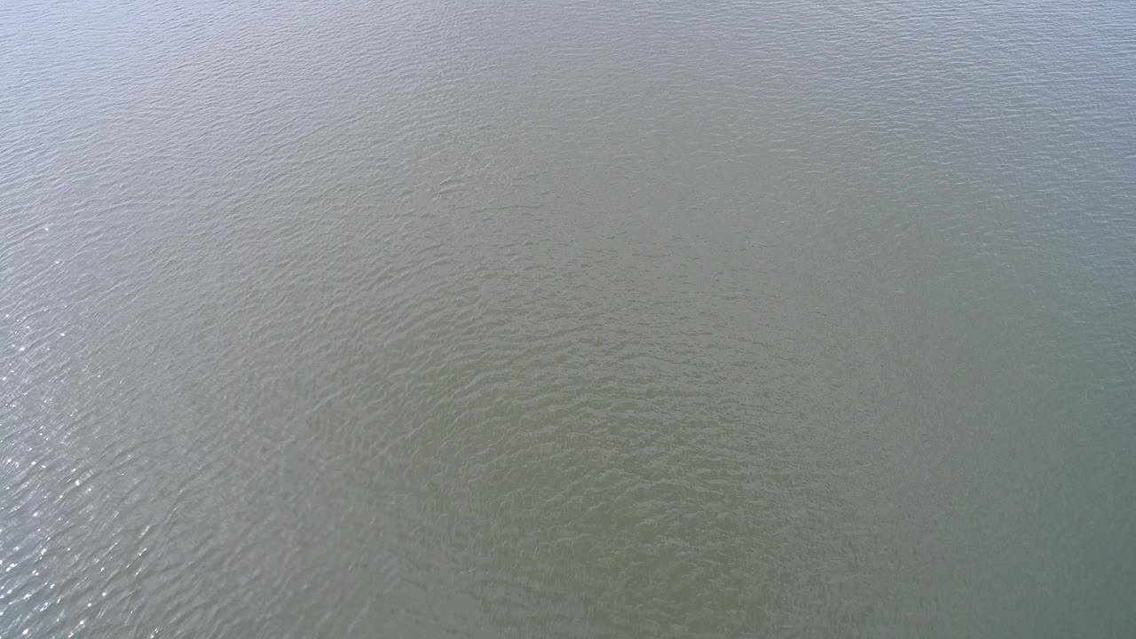 Overhead Hidden Lake, Colorado water surface with small wind ripples and a narrow bright reflection running down the middle, no visible people.
