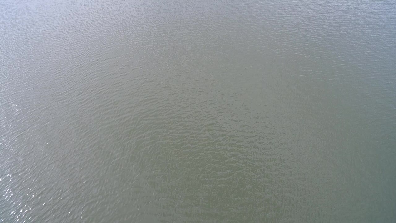Pale green-blue water surface at Hidden Lake, Colorado, with fine ripples and a bright reflected band near the left side, no visible people.