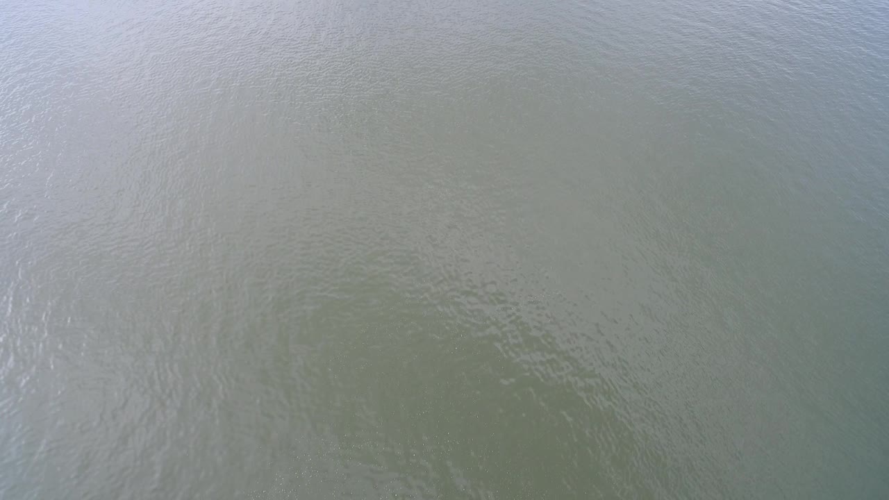 Aerial frame of Hidden Lake, Colorado water with fine surface texture, muted green color, and a lighter reflective patch near the upper area, with no visible people.