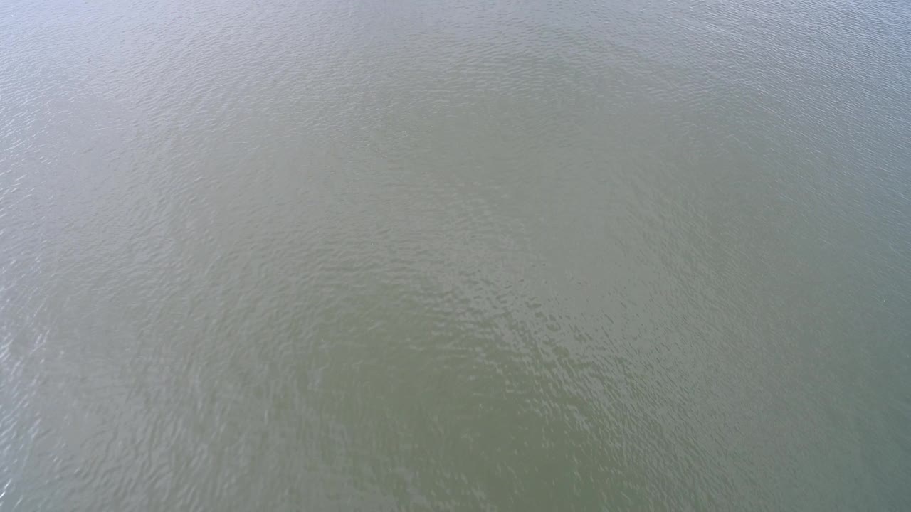 A muted section of Hidden Lake water shows pale overcast reflections across the rippled green-gray surface, with no visible people.