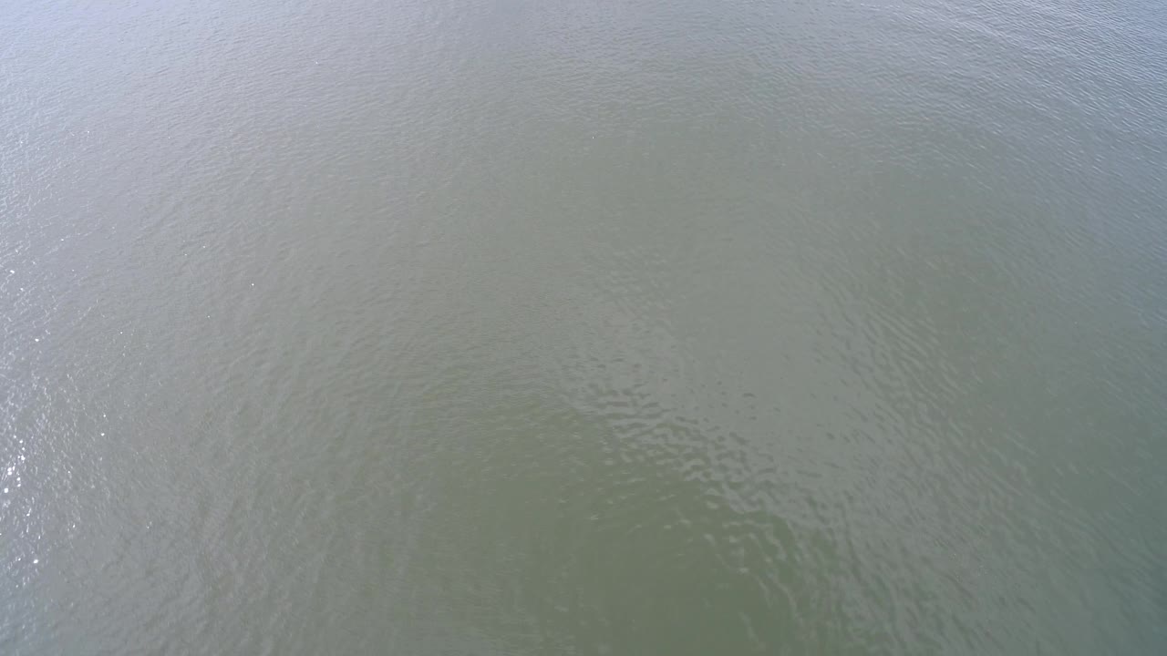 Aerial water texture with a brighter vertical sparkle patch.