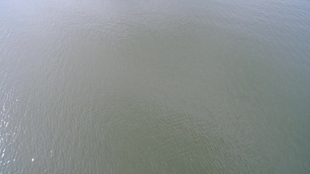 Top-down view of green-gray lake water at Hidden Lake, Colorado, with faint ripples, soft daylight glare, and no visible people.