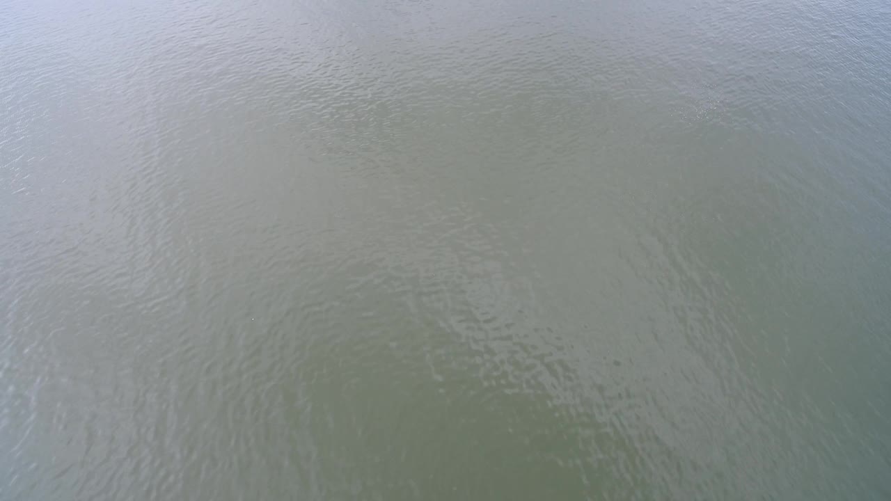 Muted green lake surface at Hidden Lake, Colorado, with a slightly darker patch beneath the ripples and no visible people.