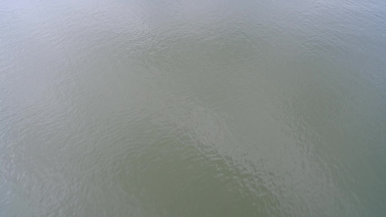 Aerial frame over Hidden Lake, Colorado, showing muted water color, small surface ripples, and a pale reflective band near the upper portion, no visible people.