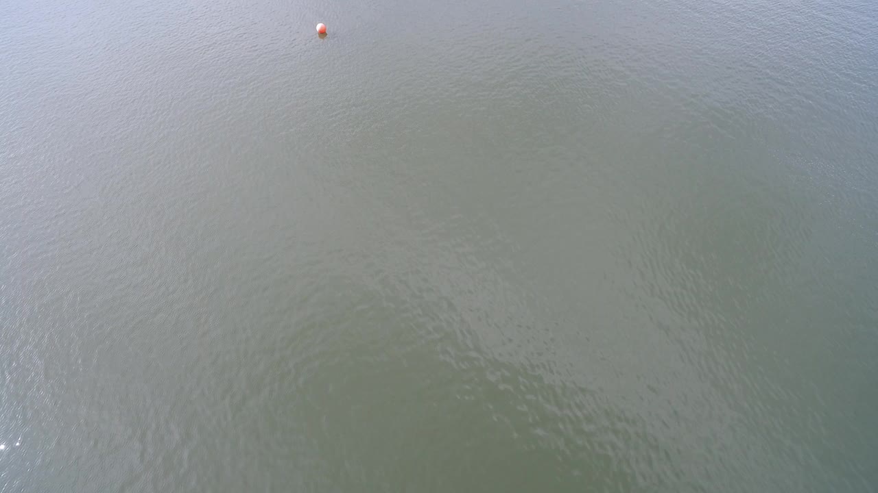 At Hidden Lake, Colorado, a small orange ball sits near the upper edge of a gray-green water surface with soft ripples and no visible people.