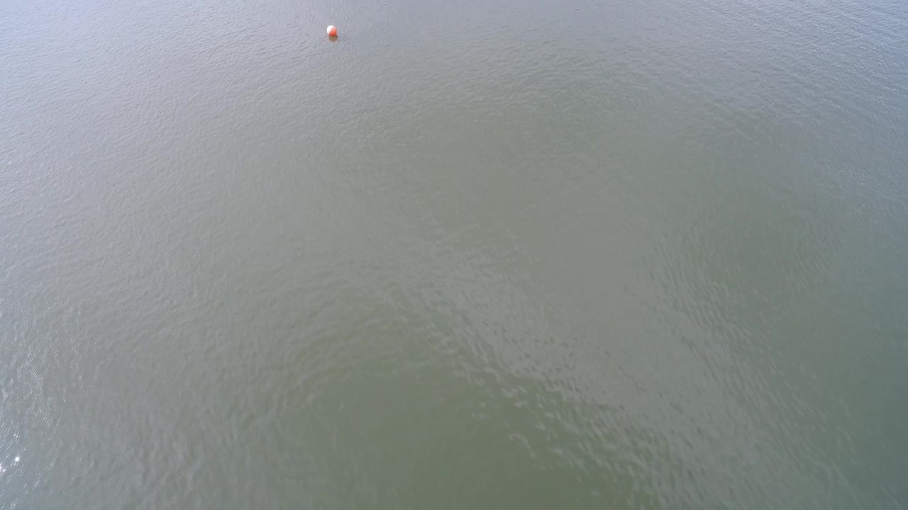 At Hidden Lake, Colorado, the orange ball remains high in frame over lightly rippled gray-green water, with no shoreline or visible people.