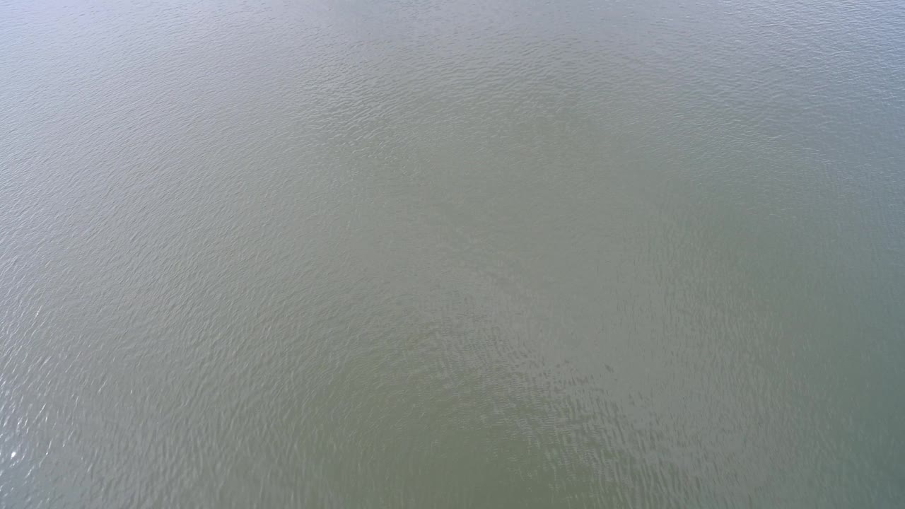 Overhead view of rippled lake water with a bright reflection band and no shoreline.