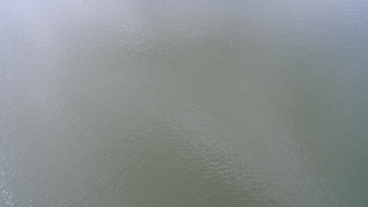 Pale green-blue water surface at Hidden Lake, Colorado, with fine ripples and soft sky reflection, no visible people.