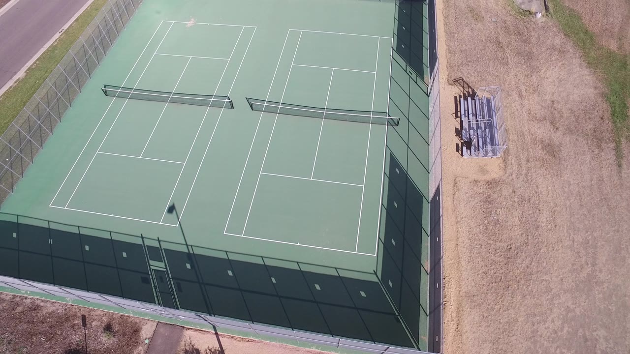 Top view of tennis courts with benches on dry ground nearby