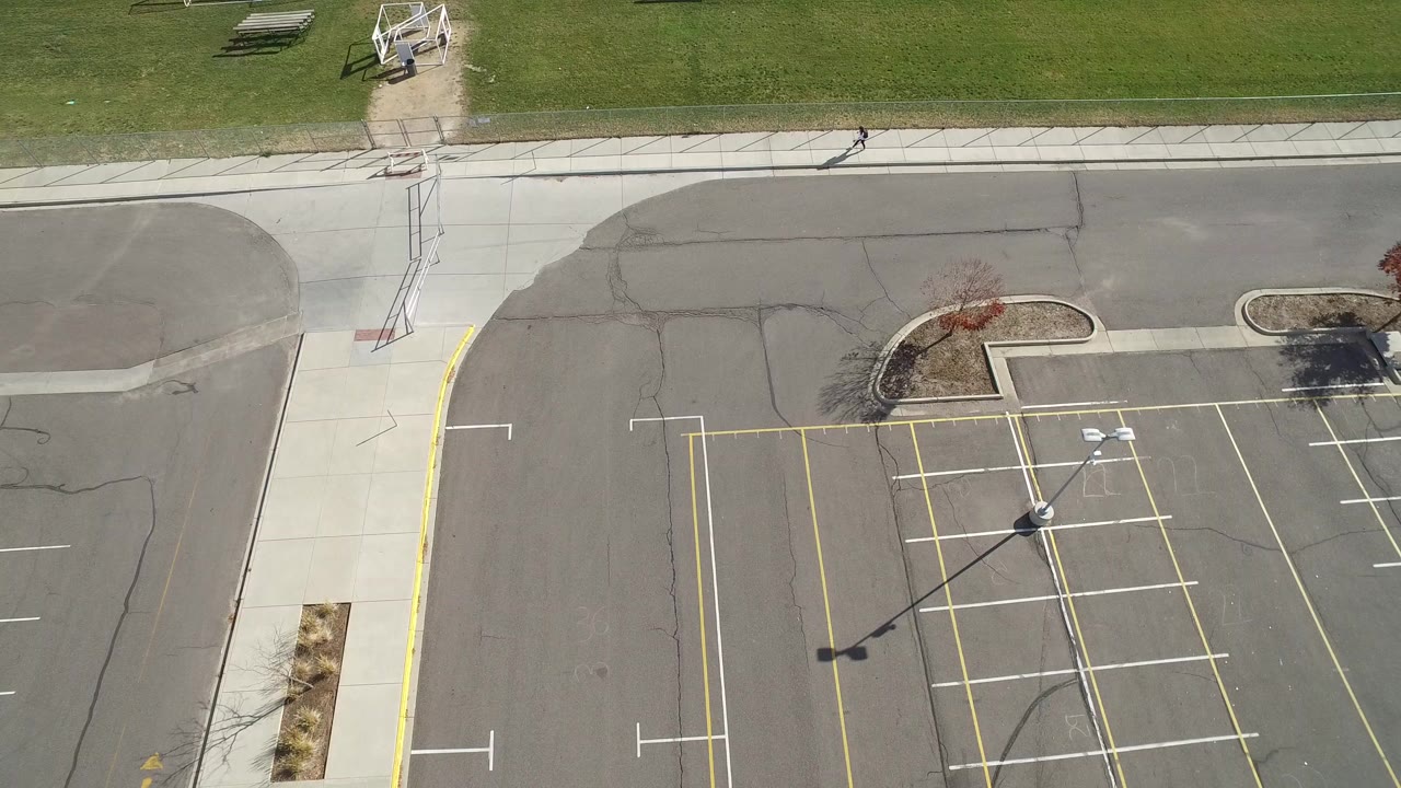 Overhead view of an empty parking lot beside grass and a sidewalk.