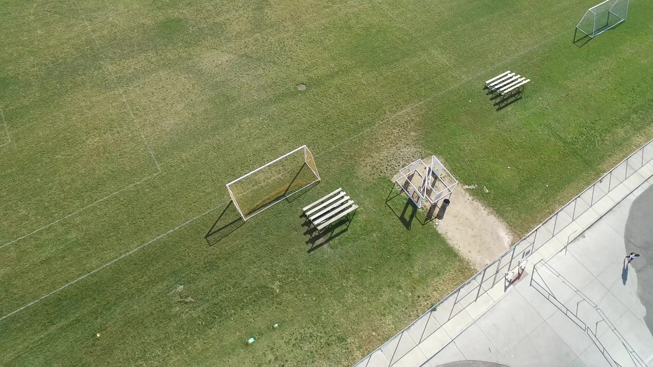 Second overhead frame in Hidden Lake, Colorado, showing the soccer goal shifted toward the lower left, bleachers beside the shelter, concrete path at right, and no visible people.