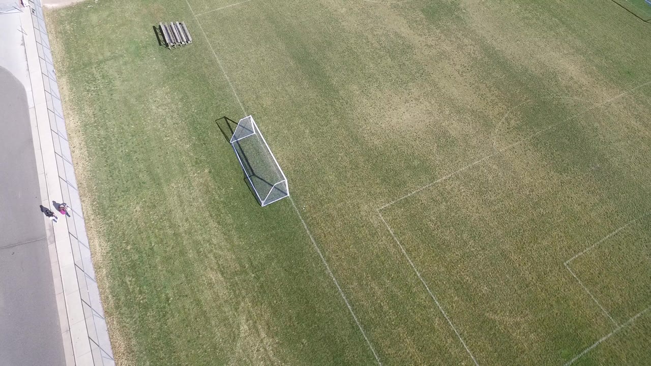 Overhead view of a soccer field beside a sidewalk and road.