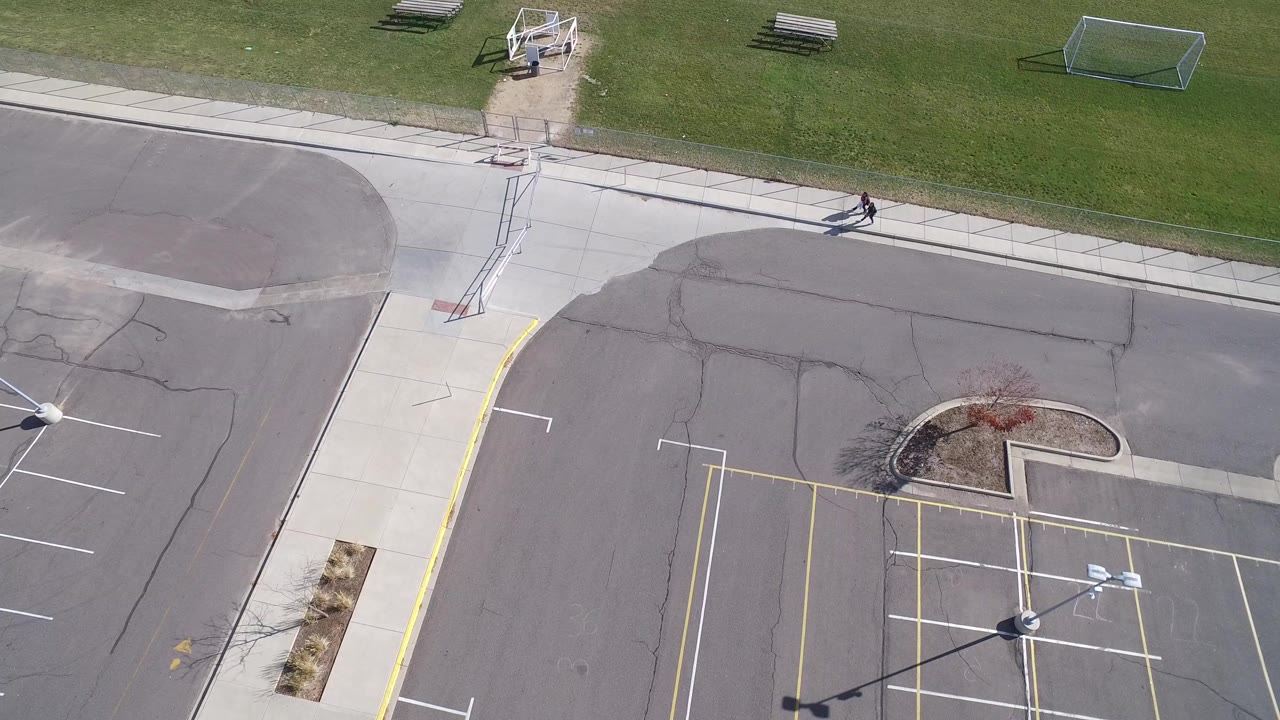High aerial view of an empty parking lot beside grass and sidewalks.