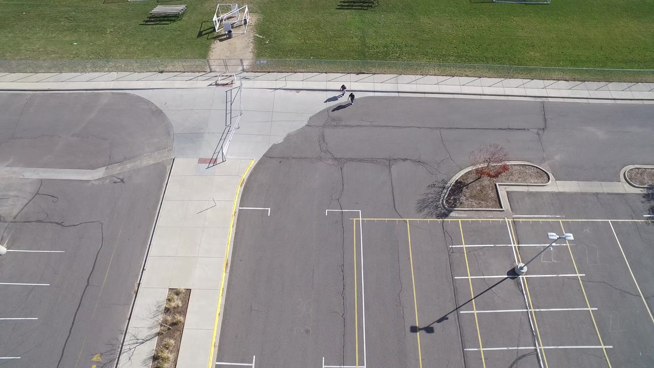 Overhead view of a parking lot beside a grassy soccer field.